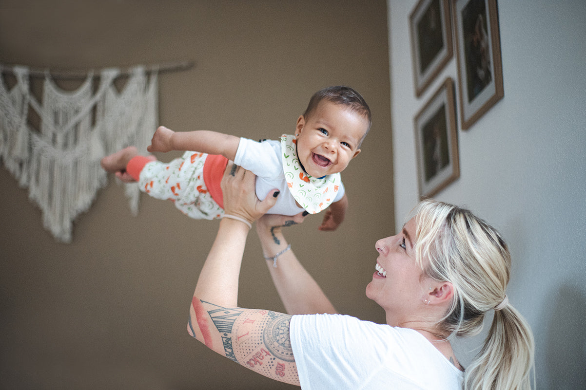 Mutter hebt Baby lachendes Baby hoch.