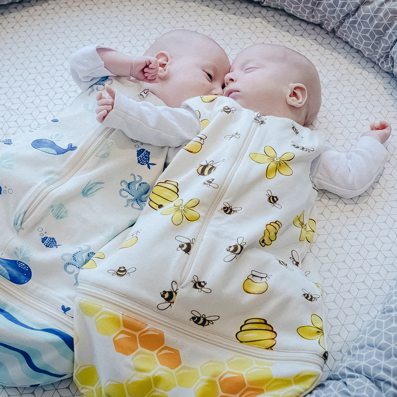 Zwei Babys schlafen nebeneinander im Windelbär Schlafsack Design Bienen und Design Meer.