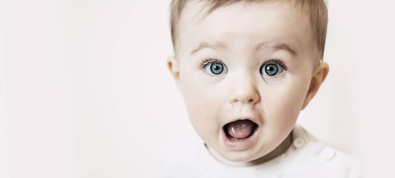 Baby mit blauen Augen, dass den Mund erquickt aufgerissen hat.