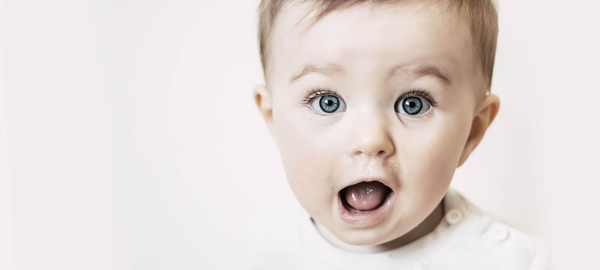 Baby mit blauen Augen, dass den Mund erquickt aufgerissen hat.